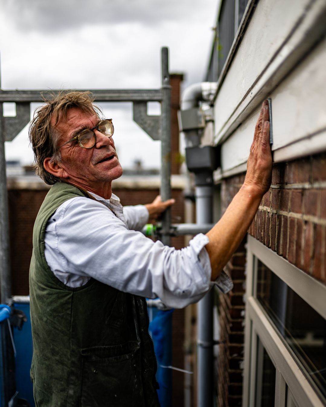 Schilder bewerkt kozijn vanaf steiger tijdens buitenschilderwerk aan woning in Rotterdam