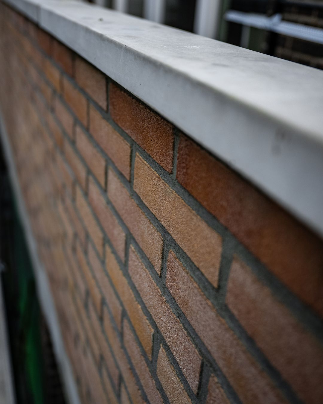 Vakman trekt halfsteens buitenmuur op met waterpas bij betonreparatie in Rotterdam door Hydro Groep