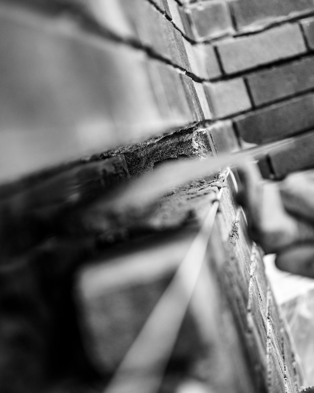 Medewerker hakt voegwerk uit met beitel en hamer op steiger bij betonreparatie in Den Haag