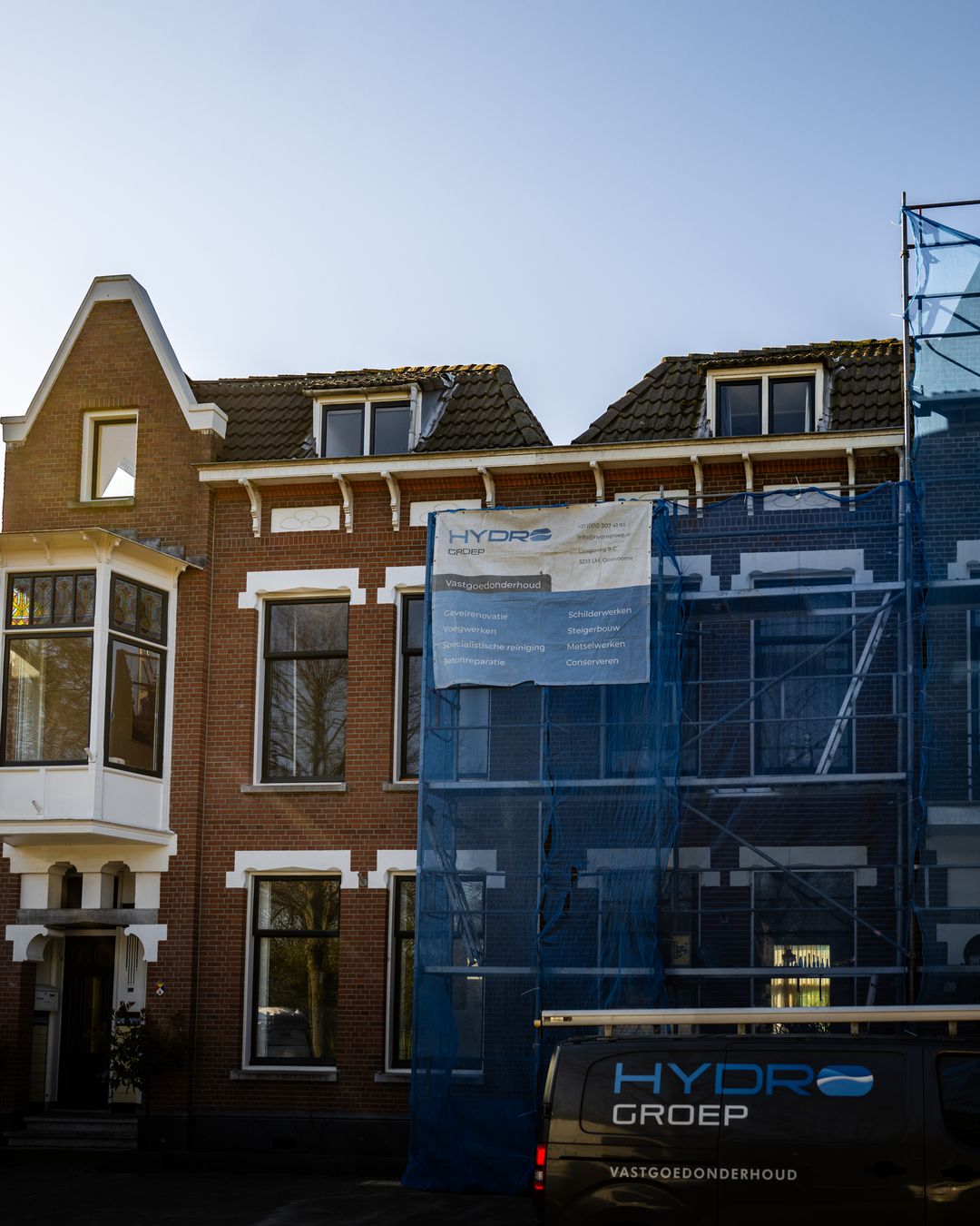 Woning aan Hofsingel met steiger, blauw gaas en Hydro Groep bus bij conserveren metselwerk Vlaardingen