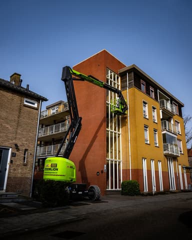 Medewerker met veiligheidshelm bouwt steiger bij appartementencomplex in Alblasserdam