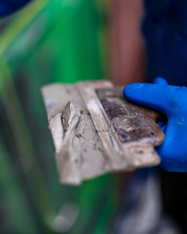 Vakman hakt oud voegwerk uit met gereedschap op steiger in Nieuw-Beijerland