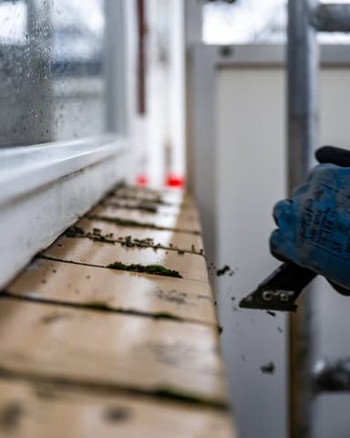 Hand reinigt raamkozijn voor vervangen van kitwerk bij VvE project in Ridderkerk