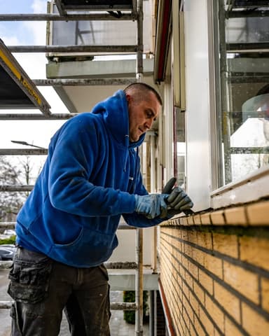 Close-up hand met schuurblok op raamdorpel bij VvE Beheer project in Ridderkerk