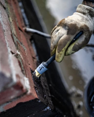 Aanbrengen waterdichte coating met kwast op fundering in Brielle voor Woonbedrijf Voorne aan Zee
