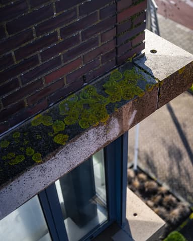 Silhouet medewerker tijdens stoomreiniging gevel vanuit hoogwerker in Monster