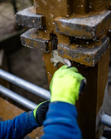 Vakman straalt betonpilaar van entreebrug met slijpmachine in Tinte door Hydro Groep