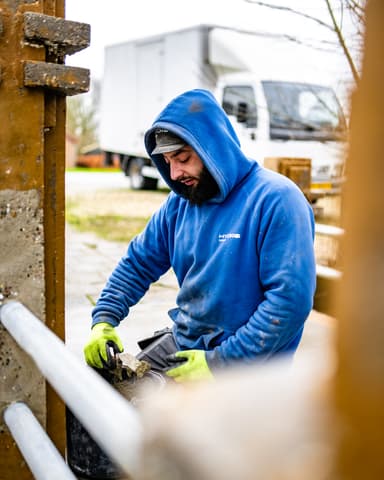 Aanbrengen reparatiemortel op betonnen brugleuning bij kerk in Tinte