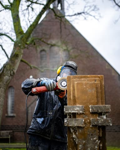 Conserveren van betonwerk vanaf steiger in beschermkleding bij kerk in Tinte