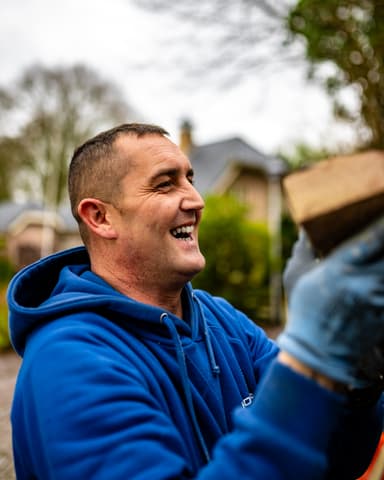 Schilder werkt aan dakkapellen op steiger met stadsgezicht in Oostvoorne