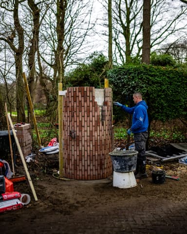 Vakman hakt voegwerk uit bij gemetselde pilaar op landgoed in Oostvoorne