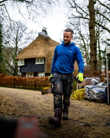 Metselaar controleert ronde pilaar met waterpas op landgoed in Oostvoorne