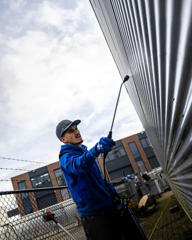 Medewerker sproeit PreClean N reinigingsmiddel op sandwichpanelen in Zoetermeer