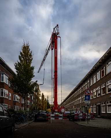 Hijskraan in straat voor steigertransport bij gevelrenovatie in Rotterdam
