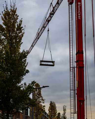 Steigermateriaal gehesen met kraan naar dak bij VvE project in Rotterdam