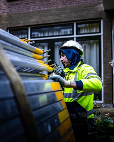 Hijskraan met steigerdeel boven Rochussenstraat tijdens gevelrenovatie in Rotterdam