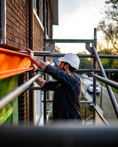 Stalen latei gehesen met kraan in schemerlicht bij woning in Vlaardingen