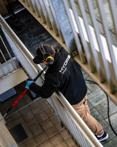Medewerker reinigt gevel met stoom op galerij van wooncomplex VvE Oostelijk Bastion in Vlaardingen