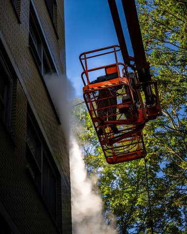 Stoomwolk tijdens gevelreiniging vanaf hoogwerker bij VvE Oostelijk Bastion in Vlaardingen
