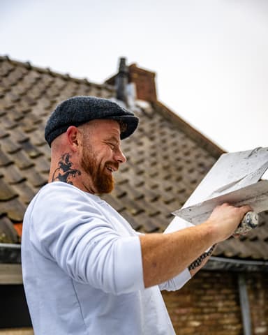 Medewerkers reinigen dakpannen vanaf hoogwerker bij gevelrenovatie in Brielle door Hydro Groep