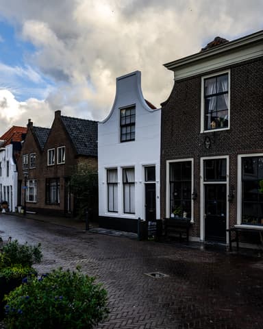 Vakman spuit stucwerk op voorgevel bij voordeur van woning in Brielle door Hydro Groep