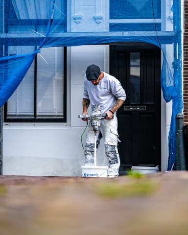 Portret van stukadoor van Hydro Groep aan het werk op steiger bij gevelstucwerk in Brielle