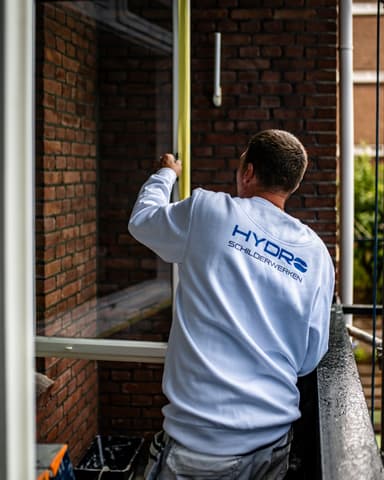 Detail afplaktape verwijderen van kozijn na buitenschilderwerk in Rotterdam door Hydro Groep