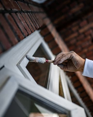 Medewerker schildert donkere gevel met roller bij buitenschilderwerk steenachtig in Rotterdam