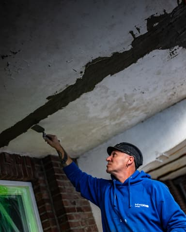 Vakman herstelt voegwerk op gevel met spaan tijdens betonreparatie in Rotterdam door Hydro Groep