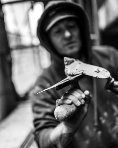 Vakman maakt voegwerk schoon met spons op steiger tijdens betonreparatie in Rotterdam