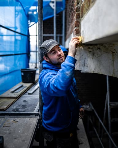 Aanbrengen menie met kwast voor corrosiebehandeling tijdens betonreparatie in Rotterdam door Hydro Groep