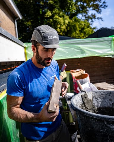 Vakman metselt bij stalen latei met spaan tijdens constructief onderhoud in Oostvoorne door Hydro Groep