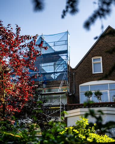 Vakman slijpt voegwerk uit met slijptol op steiger tijdens conserveren metselwerk in Rotterdam
