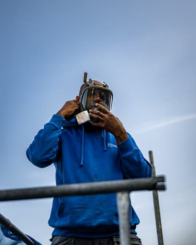 Medewerker zet volgelaatsmasker op voor stofvrij conserveren van metselwerk in Sommelsdijk