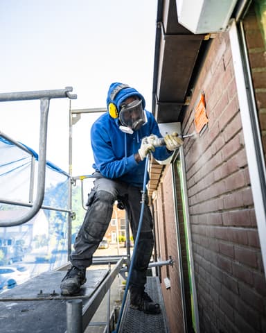 Pneumatisch uithakken van voegwerk op gevel tijdens conserveren metselwerk in Sommelsdijk