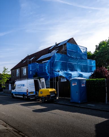 Medewerker met volgelaatsmasker werkt aan voegwerk op steiger voor conserveren metselwerk Sommelsdijk