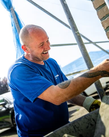 Straatnaambord Hoendiep met woning op achtergrond bij conserveren metselwerk in Dordrecht