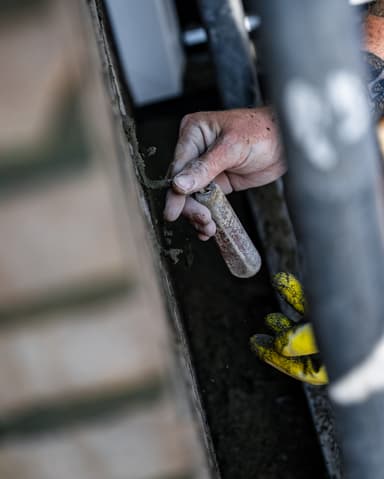 Medewerker mengt voegspecie in kuip bij gevel voor conserveren metselwerk in Dordrecht
