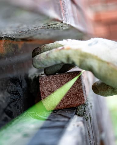 Voorgevel met steiger, blauw gaas en Hydro Groep bus bij betonreparatie in Den Haag