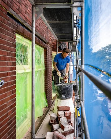 Inpassen van nieuwe steen bij lateiherstel tijdens betonreparatie aan gevel in Den Haag