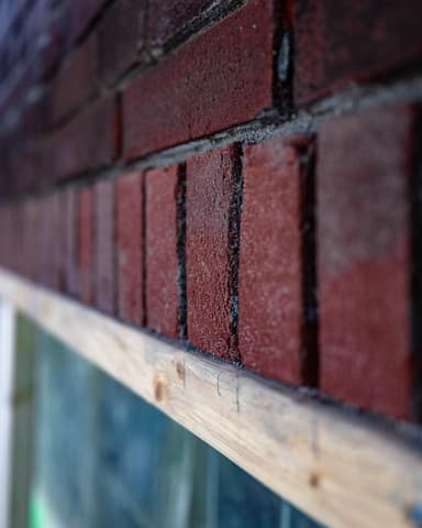 Zwart-wit close-up van uitgehakt metselwerk bij latei voor betonreparatie in Den Haag