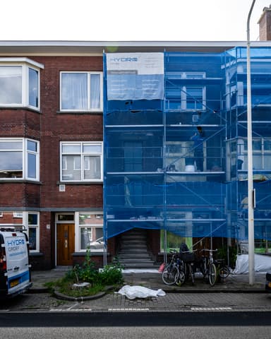 Medewerker controleert metselwerk met waterpas bij latei tijdens betonreparatie in Den Haag