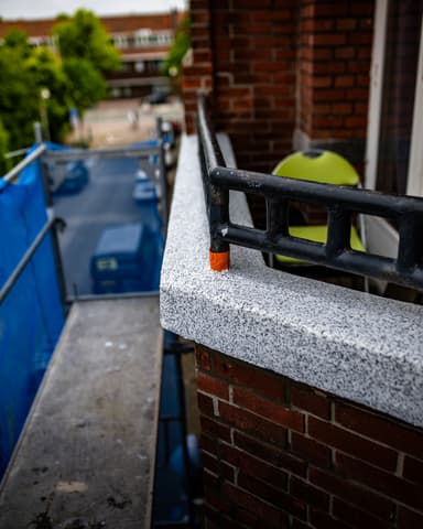 Close-up medewerker brengt voegspecie aan op hoekmetselwerk bij betonreparatie VvE Den Haag