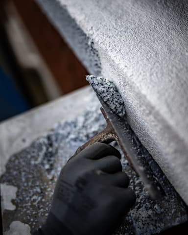 Close-up aanbrengen kunsthars granito pleister op dorpel tijdens betonreparatie VvE Den Haag