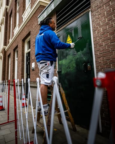Close-up hogedrukspuitkop verwijdert graffiti van wasbetontegel Stedin Rotterdam Den Haag