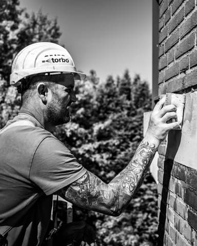 Meulemansflat met groene hoogwerker voor betonreparatie kopgevel in Tilburg door Hydro Groep