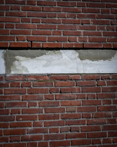 Medewerker repareert beton op kopgevel vanuit hoogwerker bij Meulemansflat in Tilburg