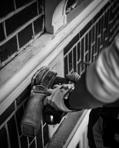 Medewerker repareert knipvoegwerk op steiger aan voorgevel Residentie Raamweg in Den Haag