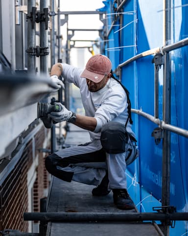 Medewerker schildert dakkapellen met uitzicht over Den Haag bij Residentie Raamweg betonreparatie