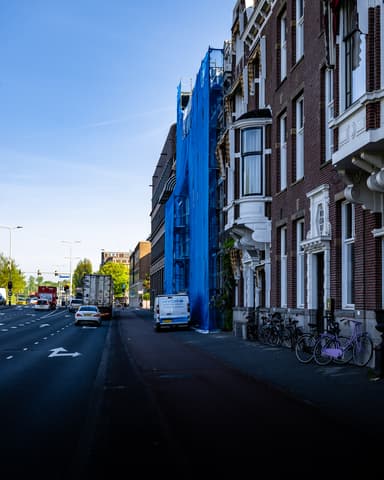 Medewerker schuurt gevelonderdeel met slijpmachine op steiger bij betonreparatie Raamweg Den Haag